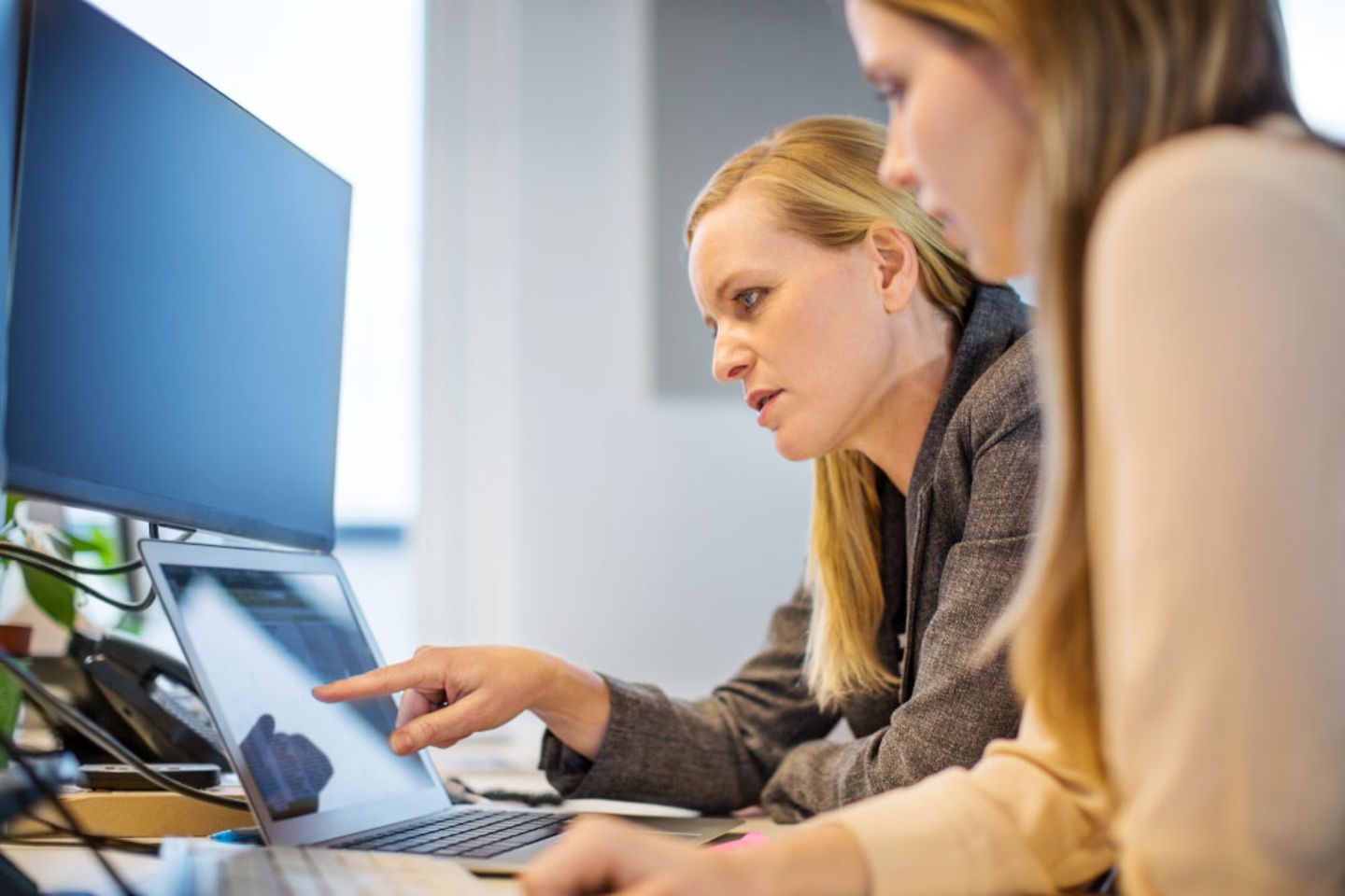 two colleagues talking to each other in front of a laptop in the office