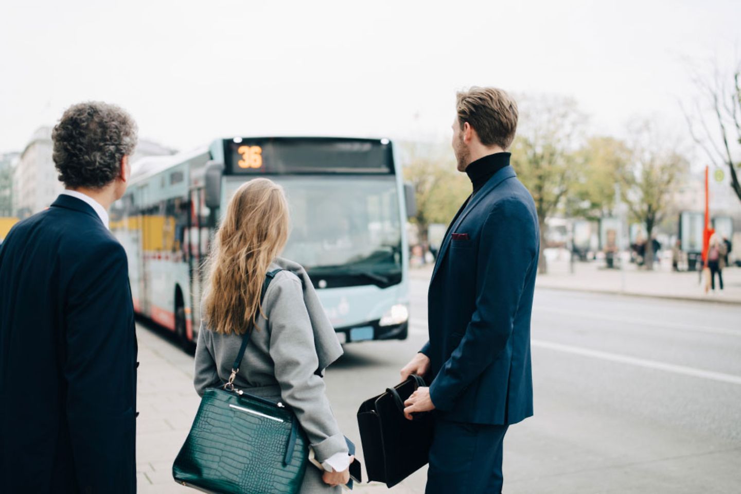 A group of businesspeople looks in the direction of a public bus in the city