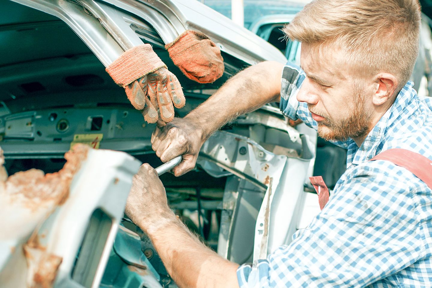 Un technicien répare une voiture avec les mains couvertes de cambouis. 