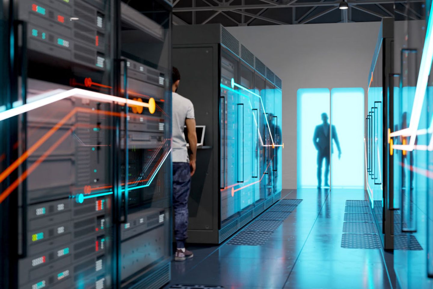 A man is standing in a server room on a laptop, another is standing behind a frosted glass door