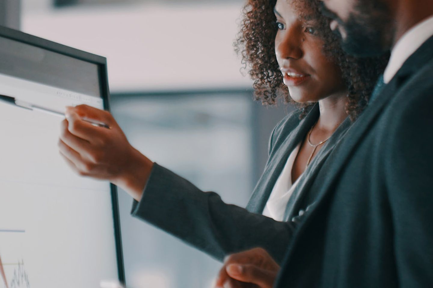 businessman and businesswoman using an interactive whiteboard to analyse data