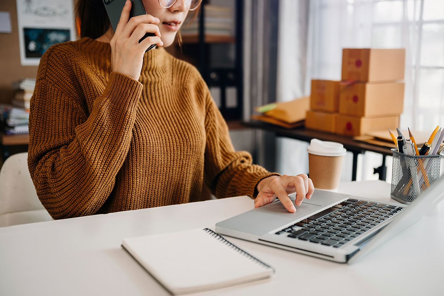 SME owner using laptop while on the phone