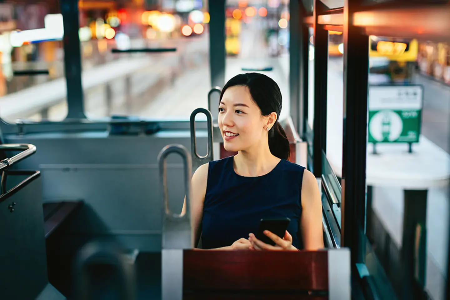Mujer con un smartphone disfrutando de las vistas de la ciudad durante un viaje en transporte público