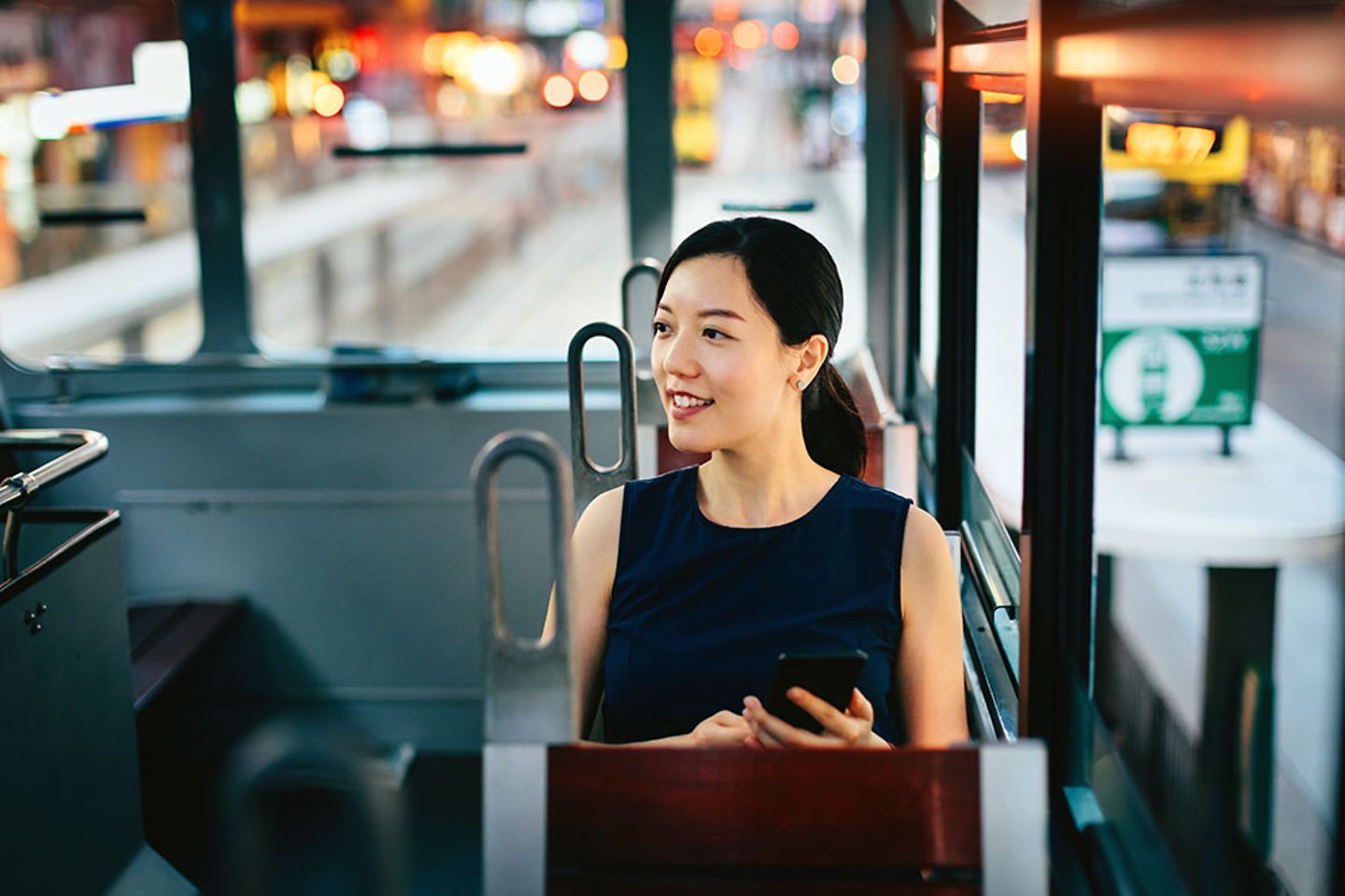 Frau mit Smartphone geniesst Stadtszene waehrend der Fahrt in oeffentlichen Verkehrsmitteln