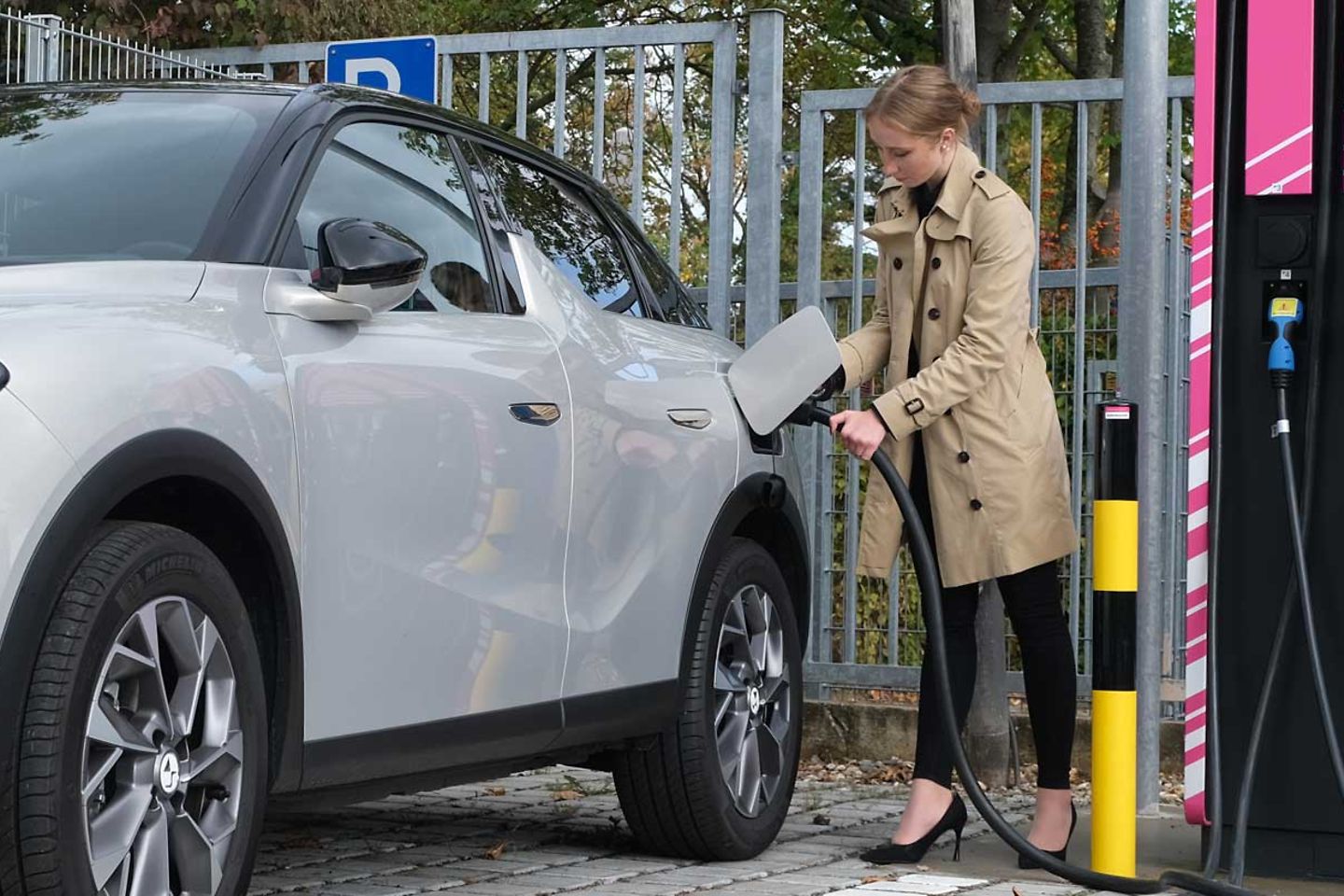 A woman charges her car at a ComfortCharge charging station