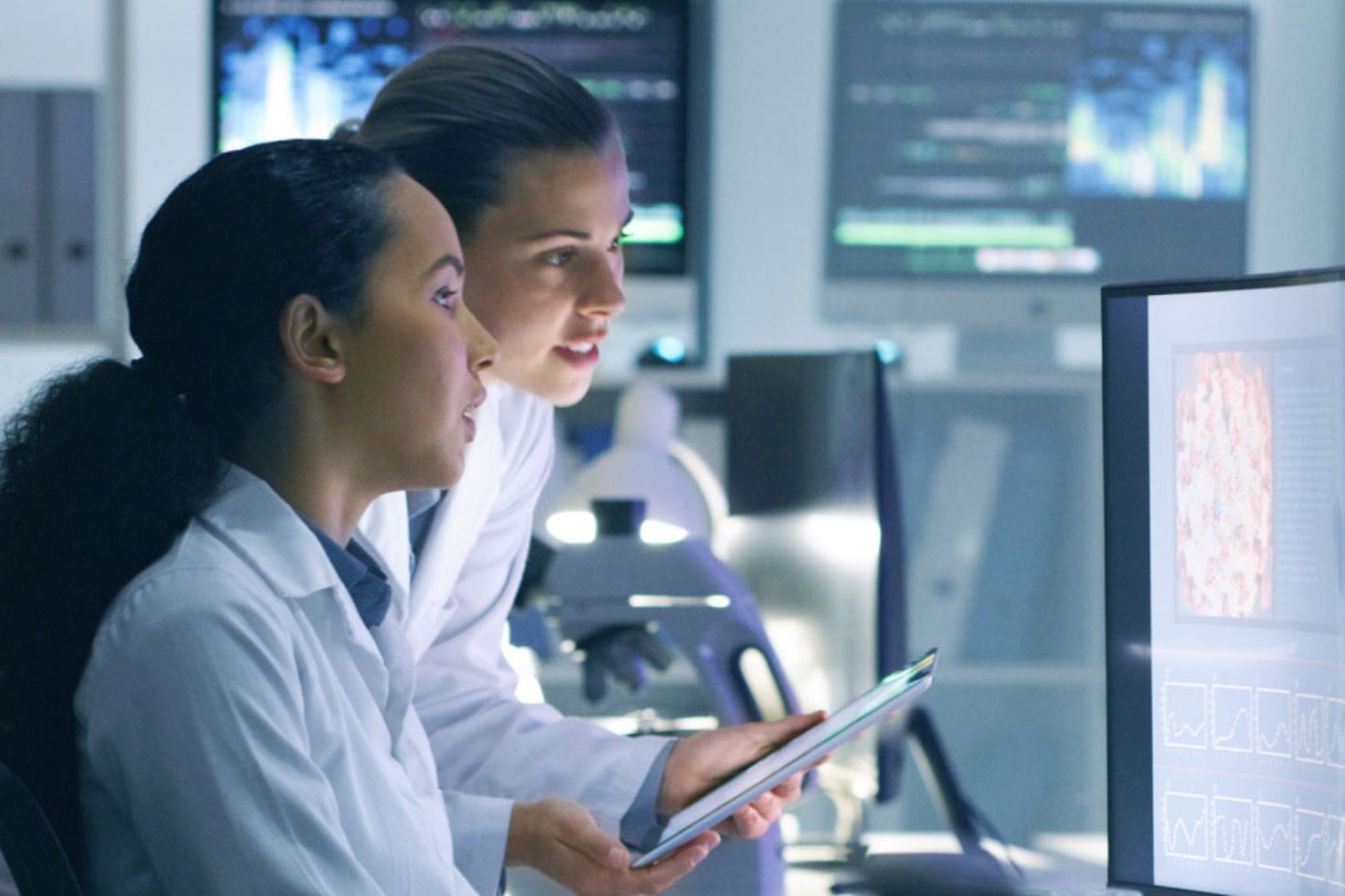 Two doctors are looking at something on a screen. One has a tablet in his hand.