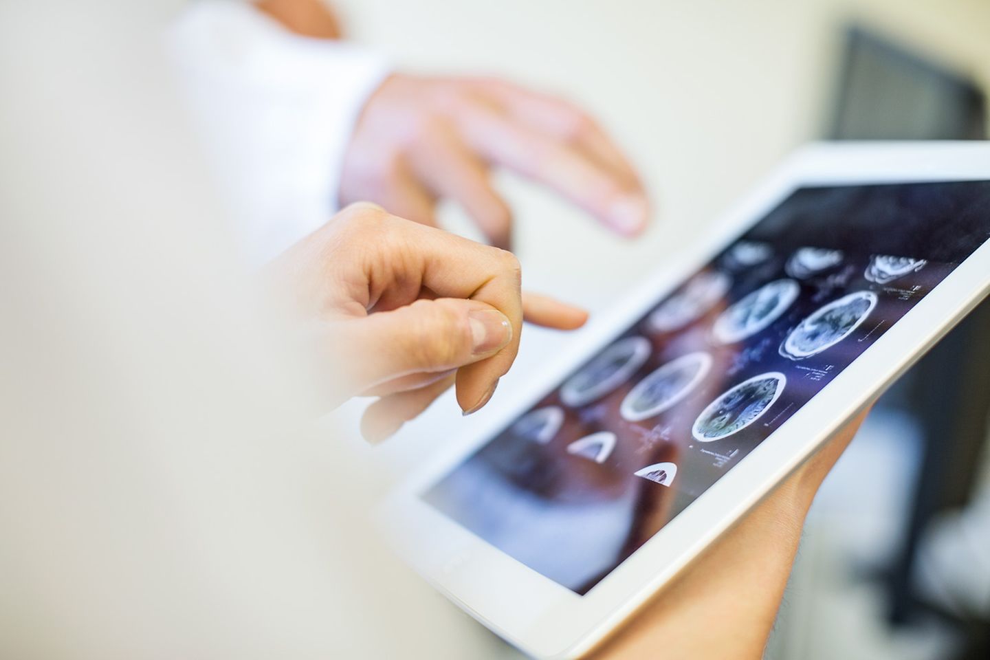Zwei Ärzte bewerten eine MRT-Aufnahme auf einem Tablet