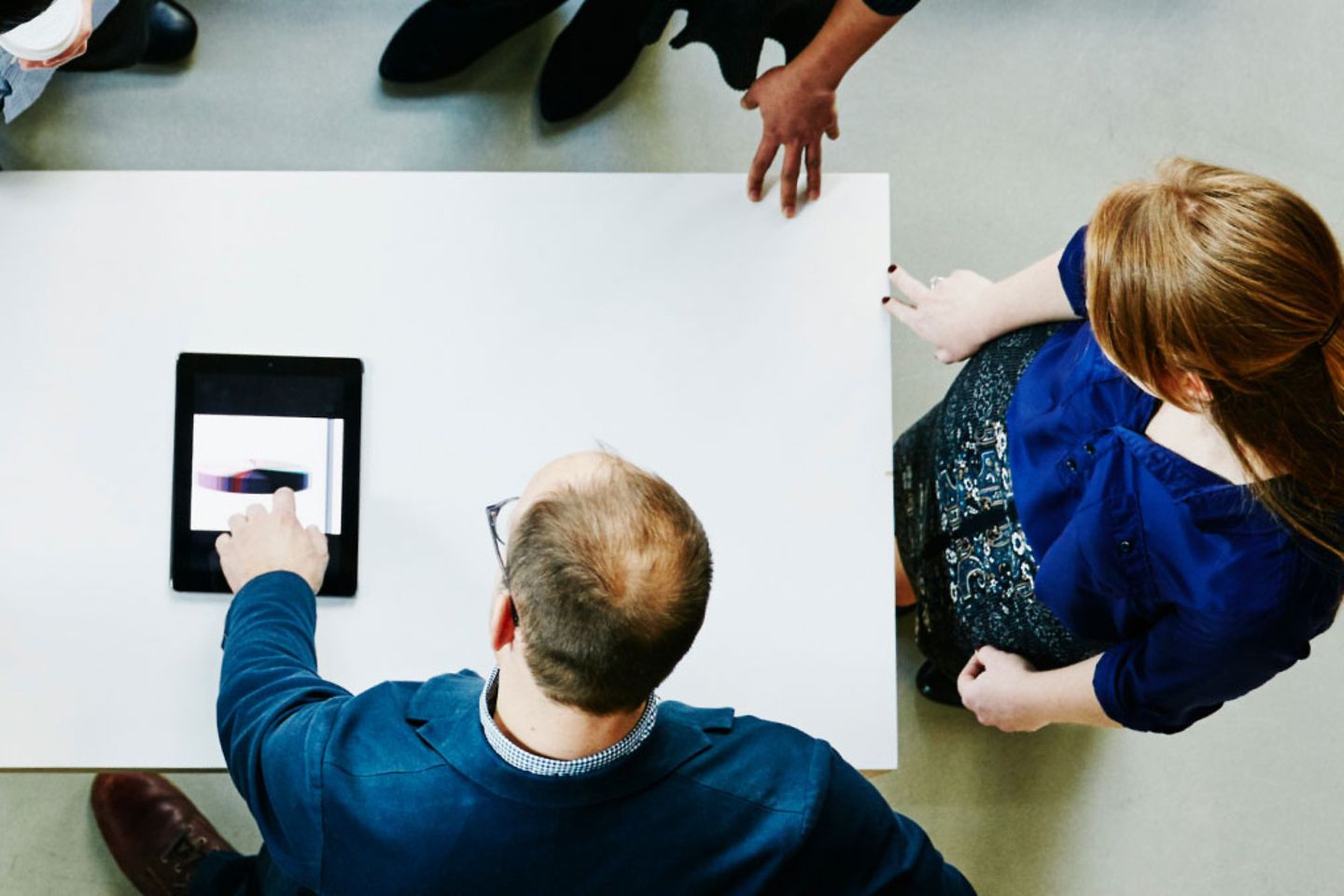 A group bends over a table with a tablet