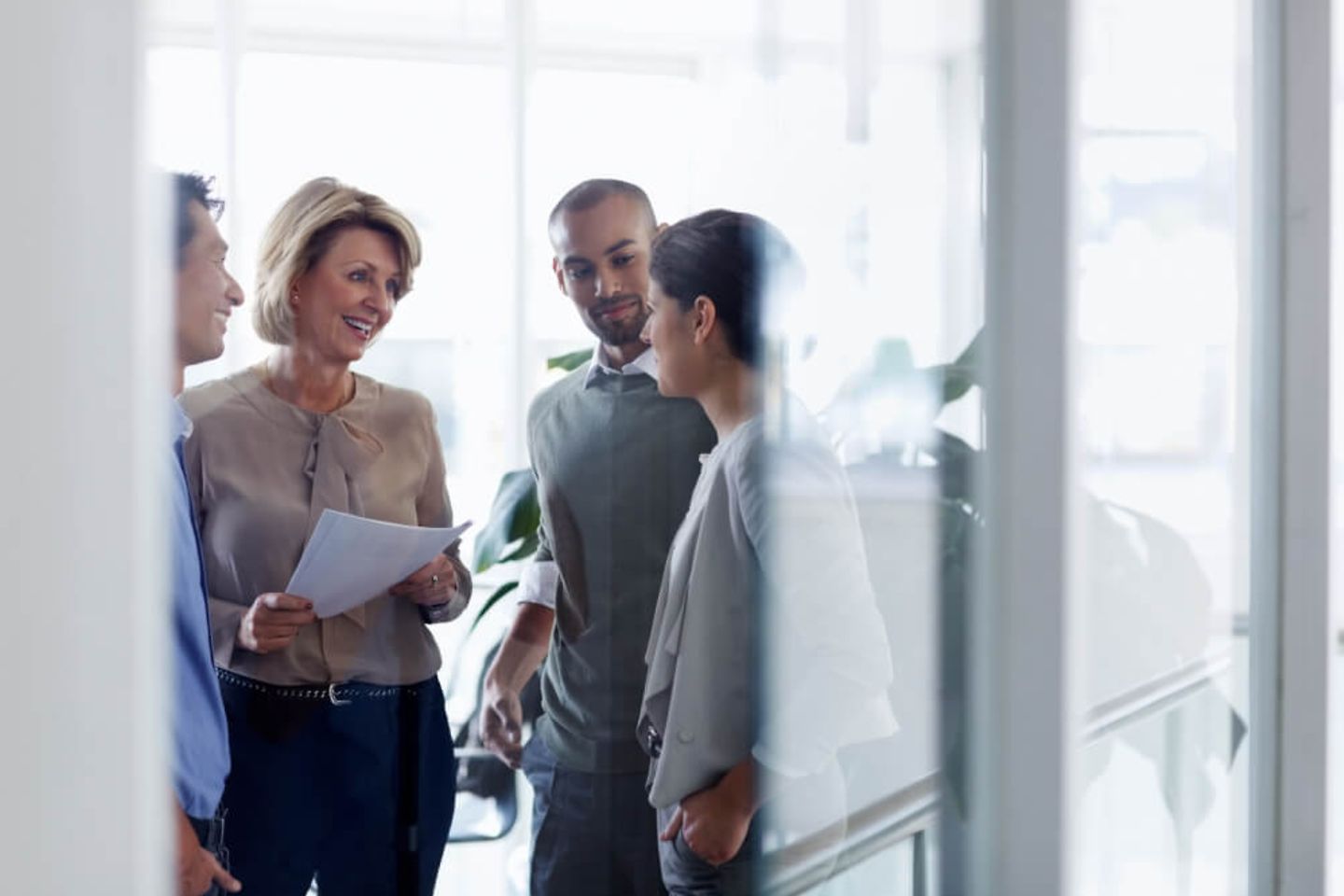 four people standing in an office talking 