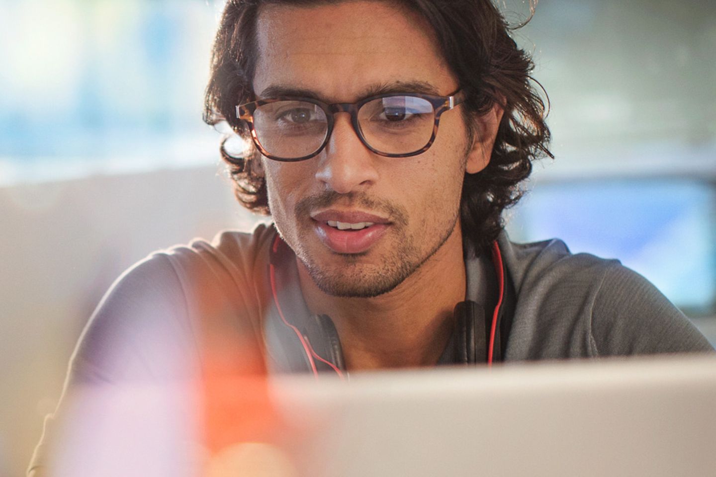 Young man sitting at his desk looking spellbound at the laptop screen