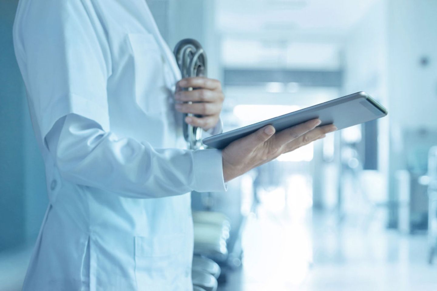 Doctor in gown with stethoscope in one hand and tablet in the other