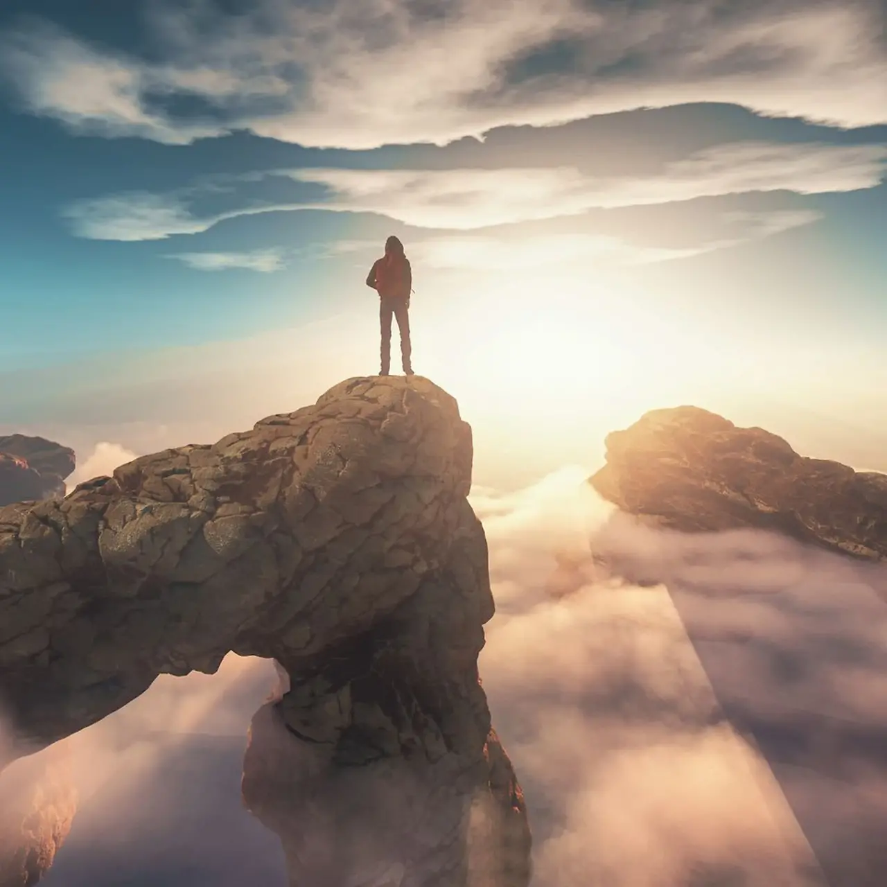 Un homme se tient au sommet d'une montagne au-dessus des nuages