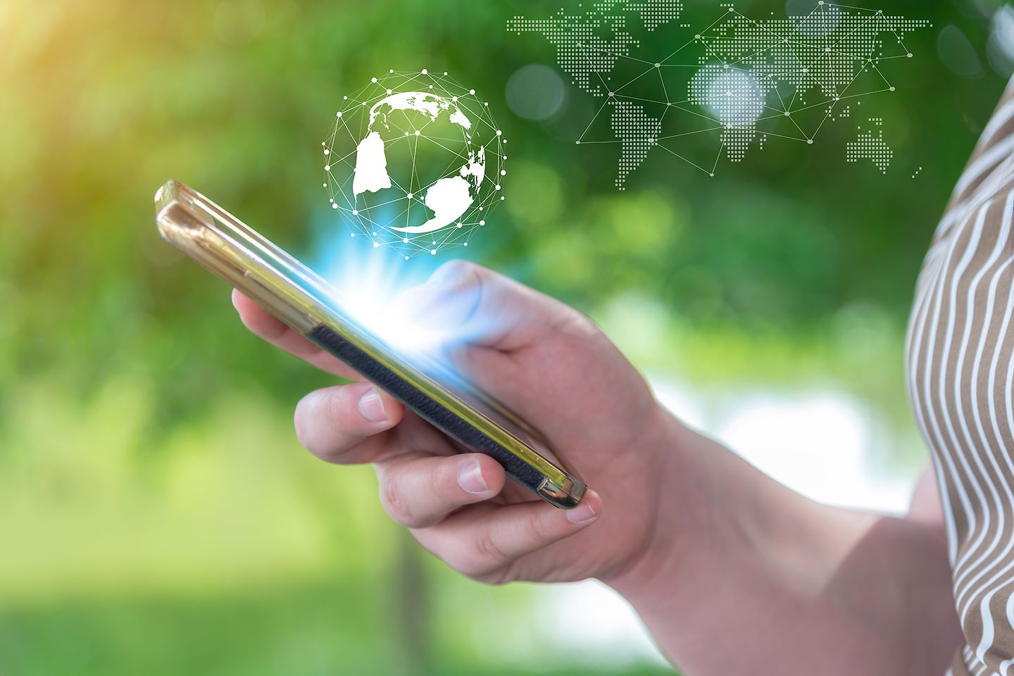 hand holding smartphone with globe icon against green background