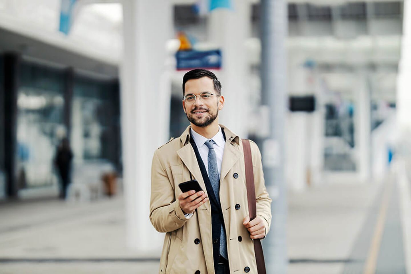 Man in business outfit standing on the track with smartphone in his hand