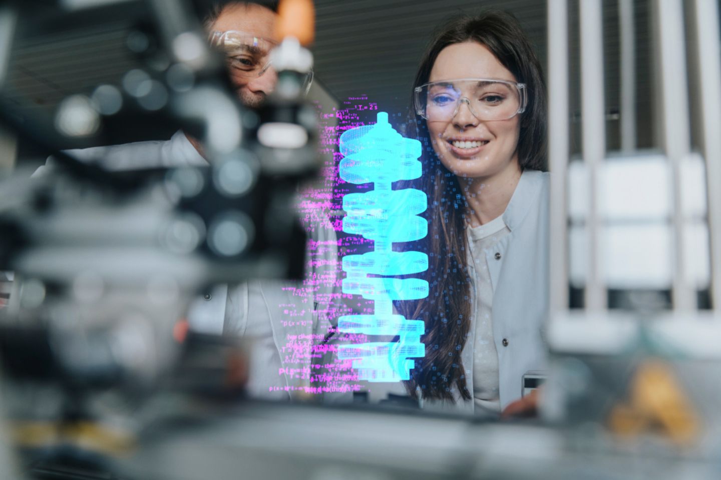 Lächelnde Ingenieurin und Ingenieur bei Untersuchung einer futuristischen Automatisierung in einem Labor