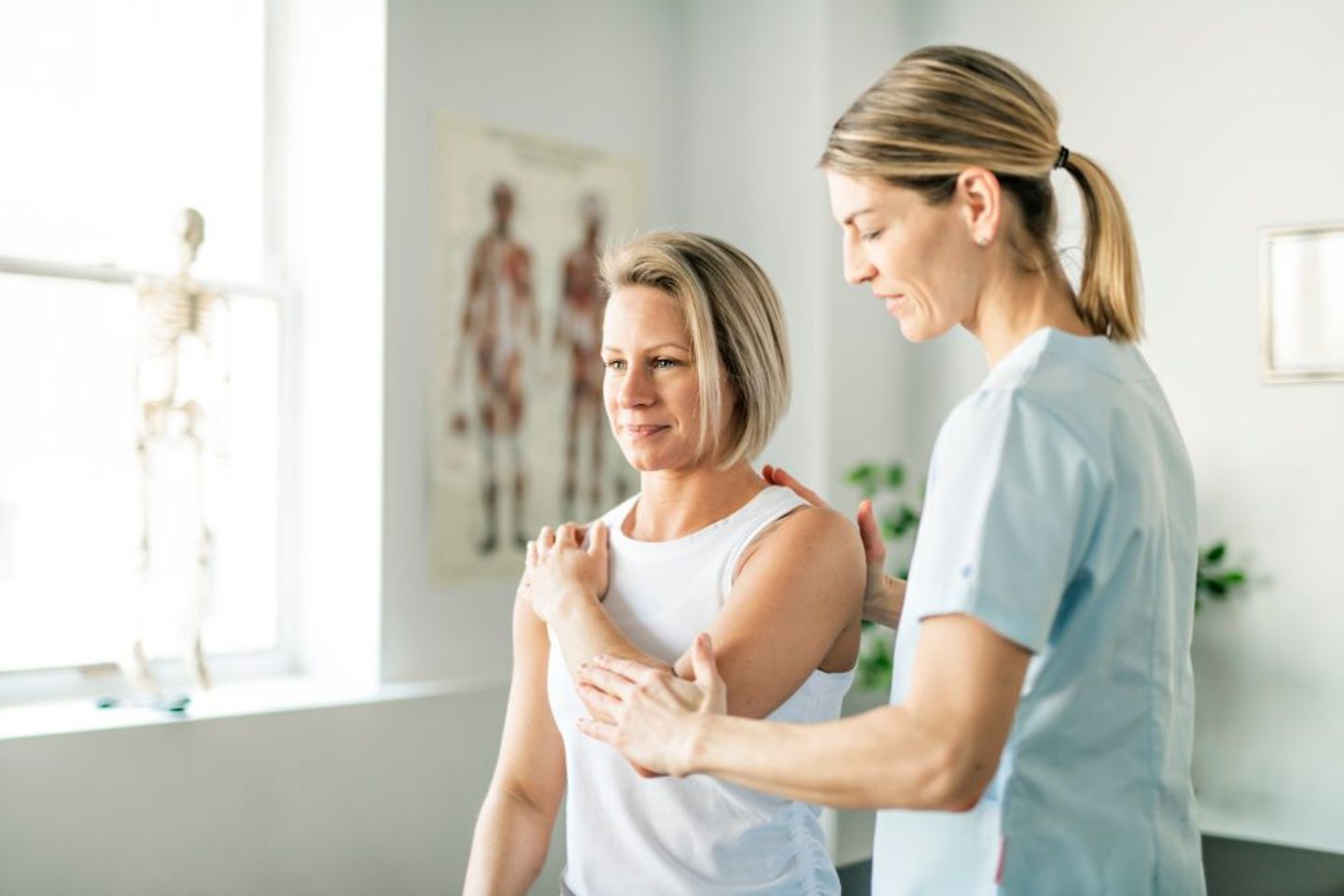 Krankenschwester hilft Patientin mit Physiotherapie und digitalen Hilfsmitteln