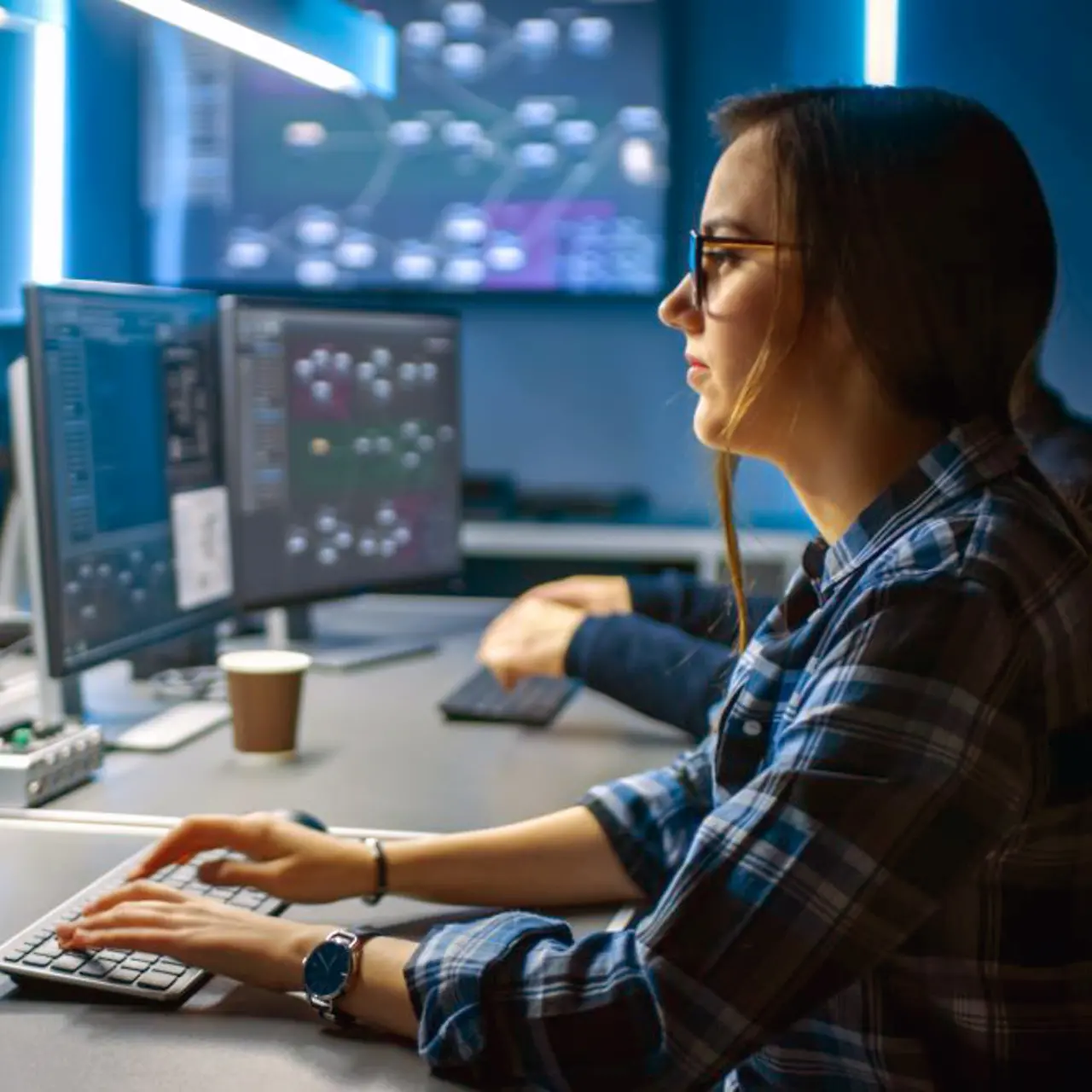 Junge Cyber Security Analystin vor dem Monitor im Security Operations Center