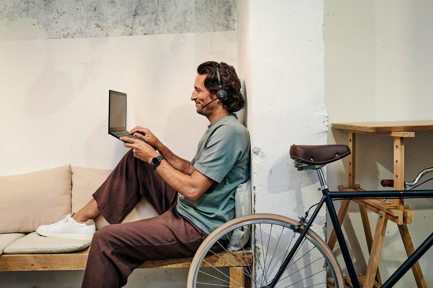 Man wearing headset sits with a laptop on the sofa