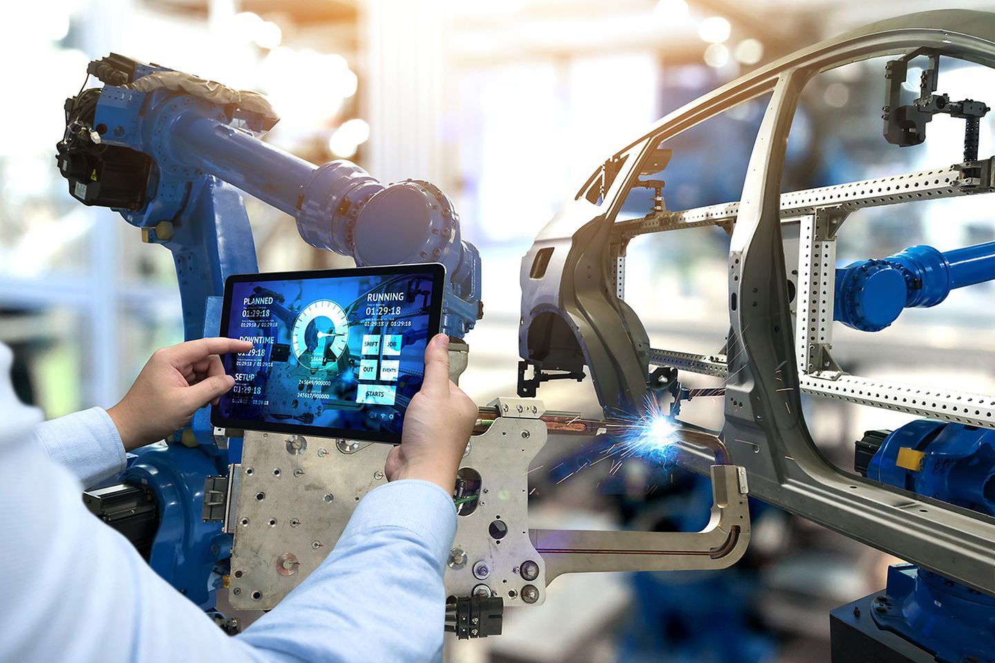  Roboterarm und Tablet in einer Autofabrik.