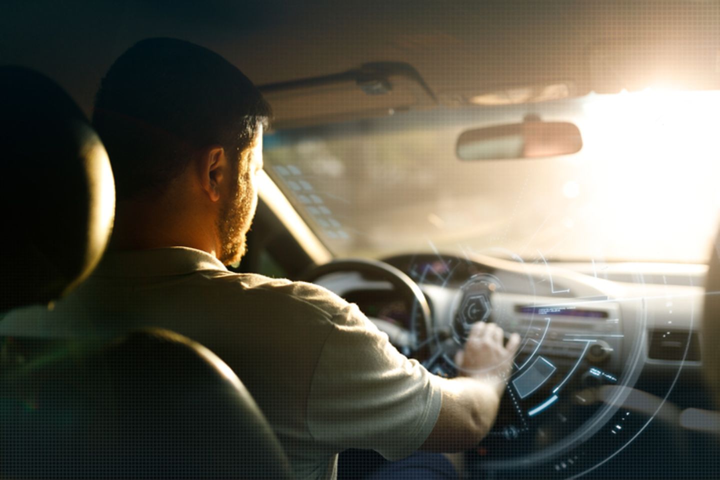 Rear view of driver, who is reaching towards the dashboard with virtual icons. Sun coming from the front.