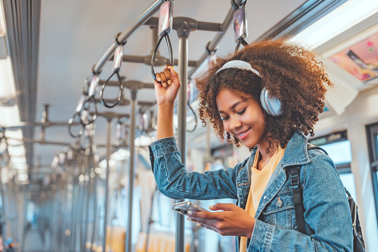 Glücklich aussehende Passagierin, die in einem Zug mit ihrem Smartphone Musik hört