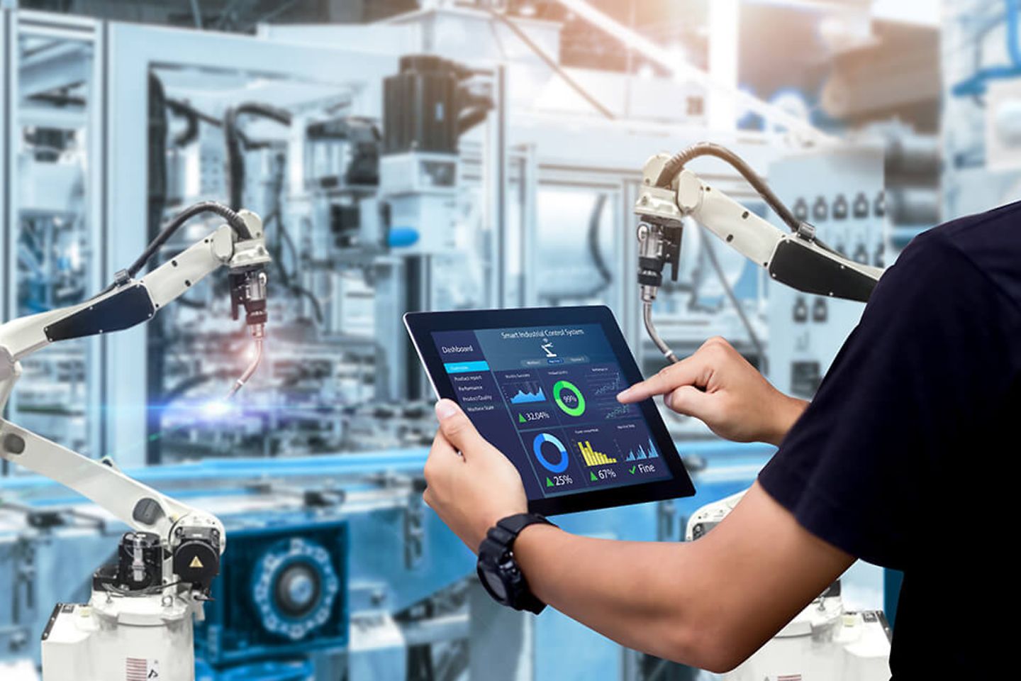 Man with tablet stands in production surrounded by industrial robots