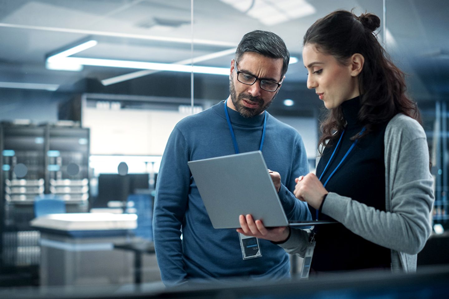 Two engineers use a laptop and analyze hybrid cloud services