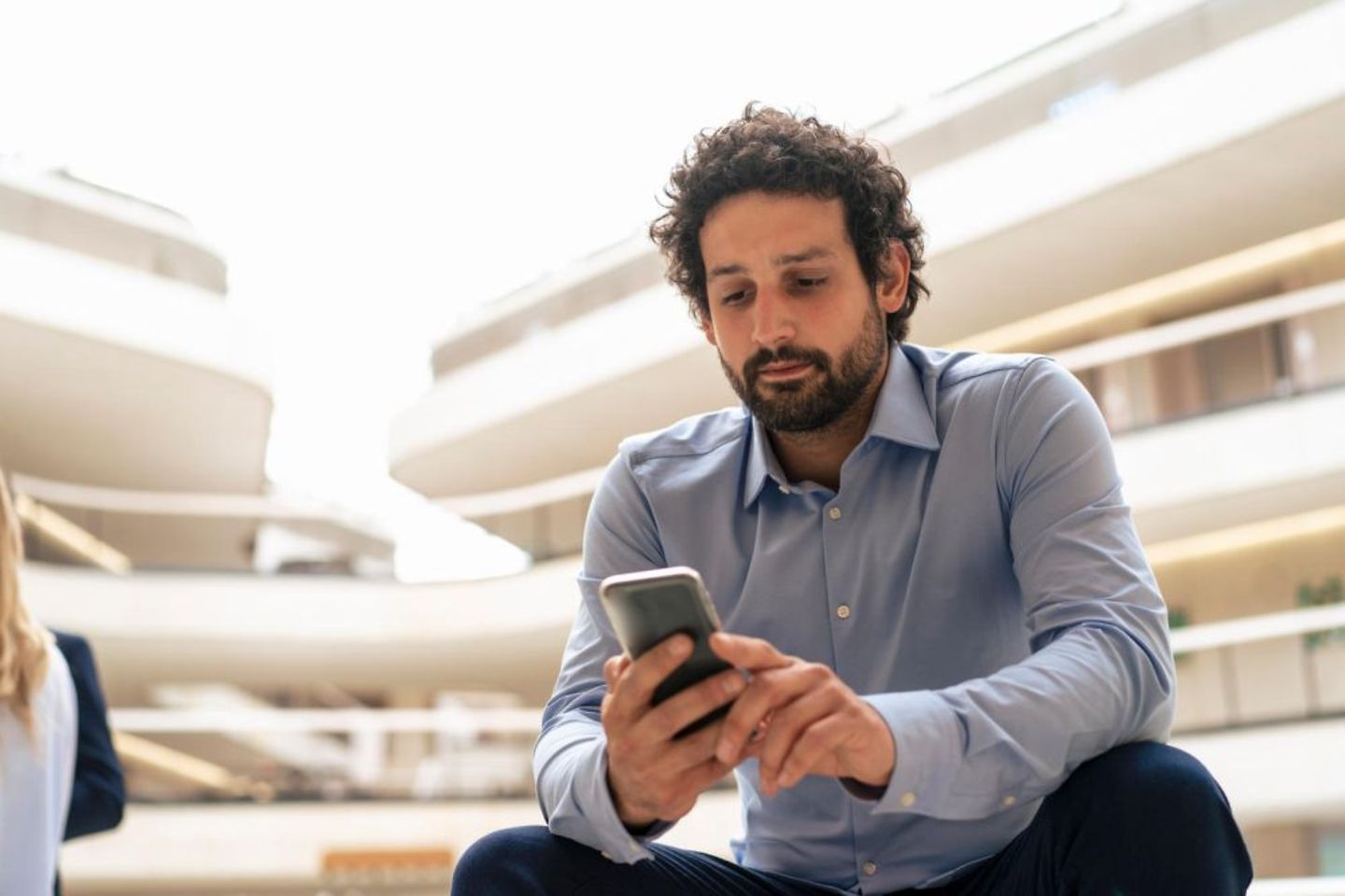Man using smartphone for online banking in office surrounding