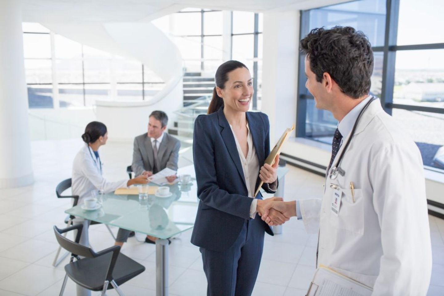 HR Business Partner Managerin im Krankenhaus schüttelt Arzt die Hand nach Gespräch zu Personalprozessen