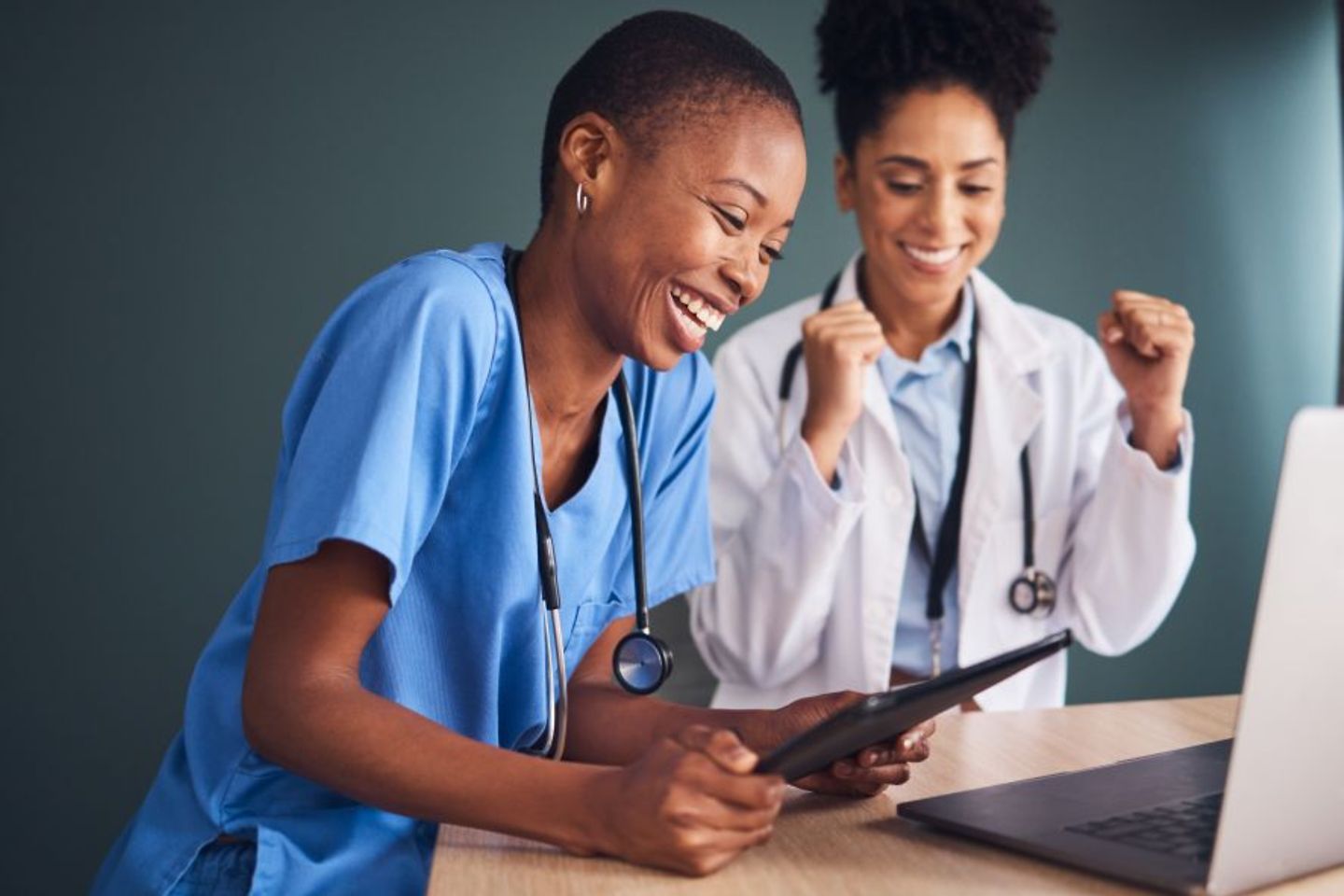 Doctors nurses celebrate success for healthcare goals in hospital in front of digital tablet and laptop