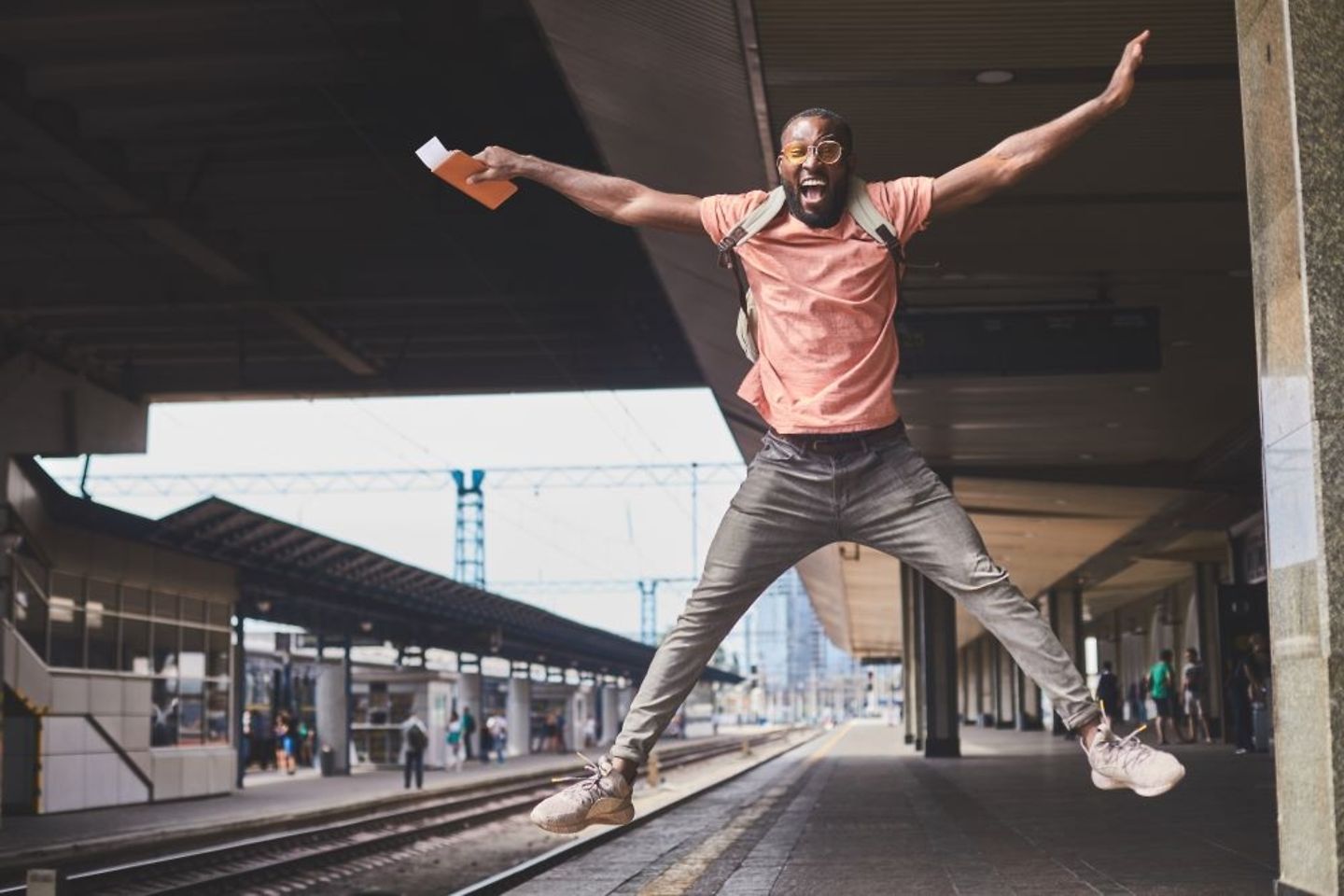 Un viajero saltando en la estación y celebrando su éxito 
