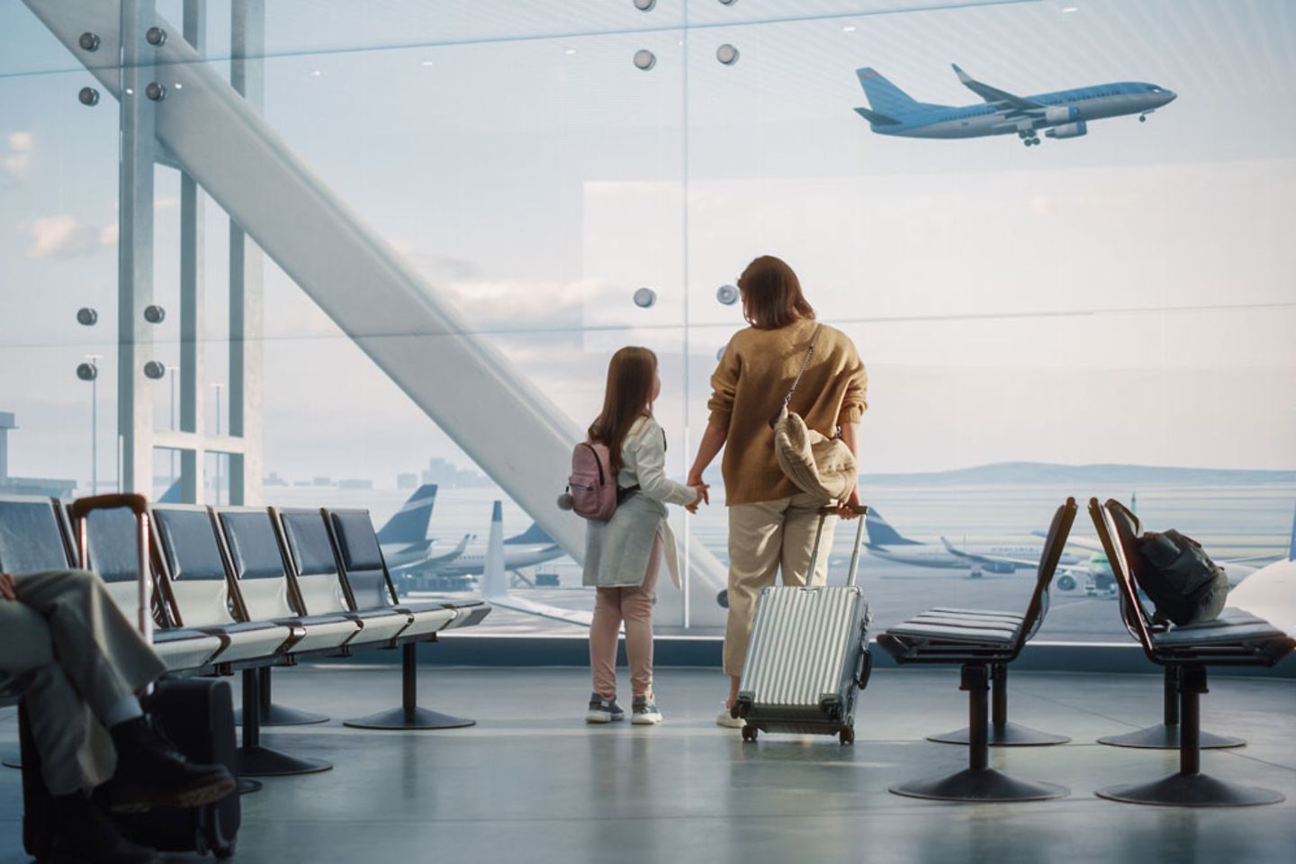 Moeder en dochter staan bij het raam in de wachtruimte op het vliegveld en kijken naar opstijgende en landende vliegtuigen