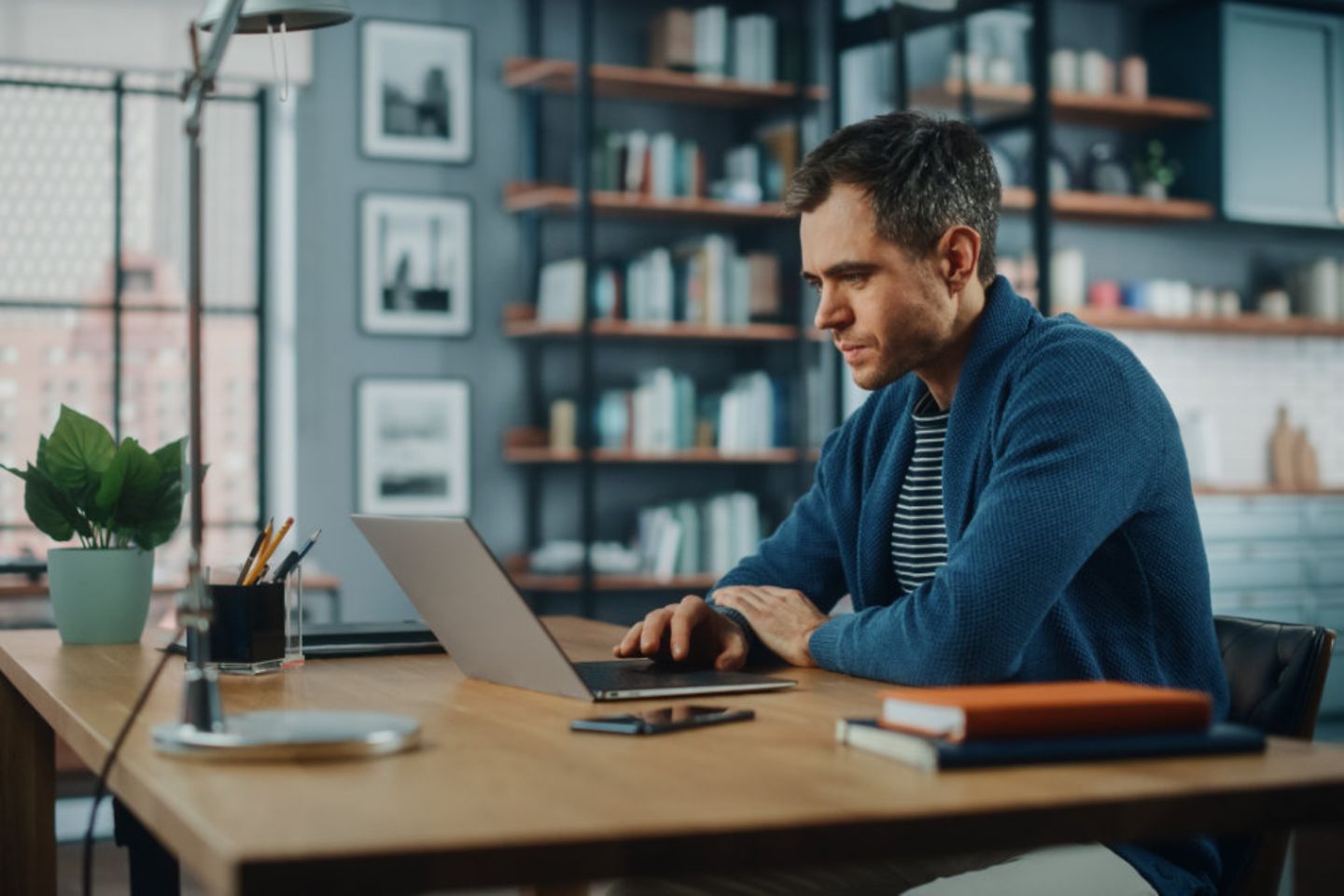 Mann arbeitet von zu Hause aus am Laptop, hybrides Arbeiten