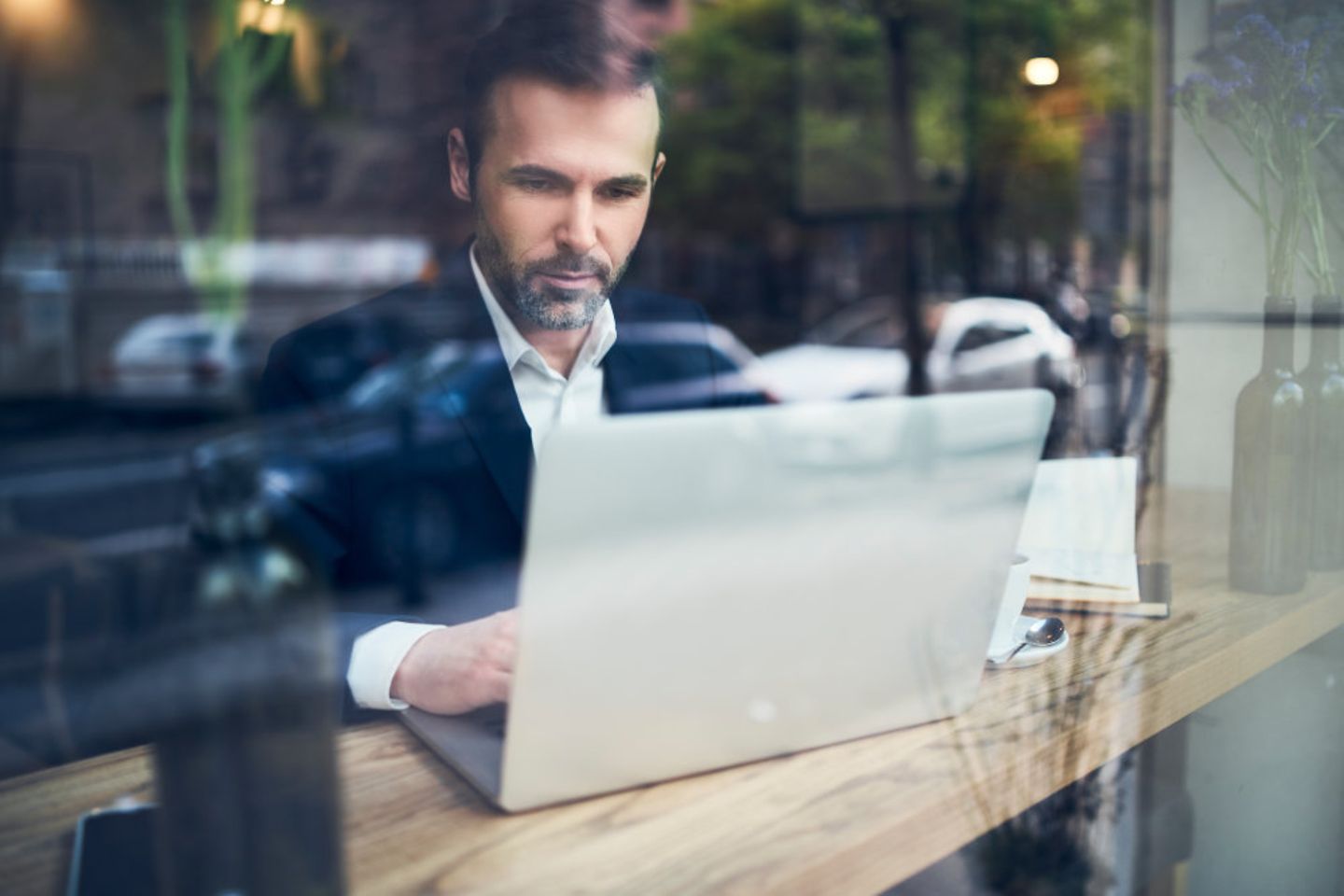 Geschäftsmann, der an einem Laptop arbeitet und in einem Cafe sitzt