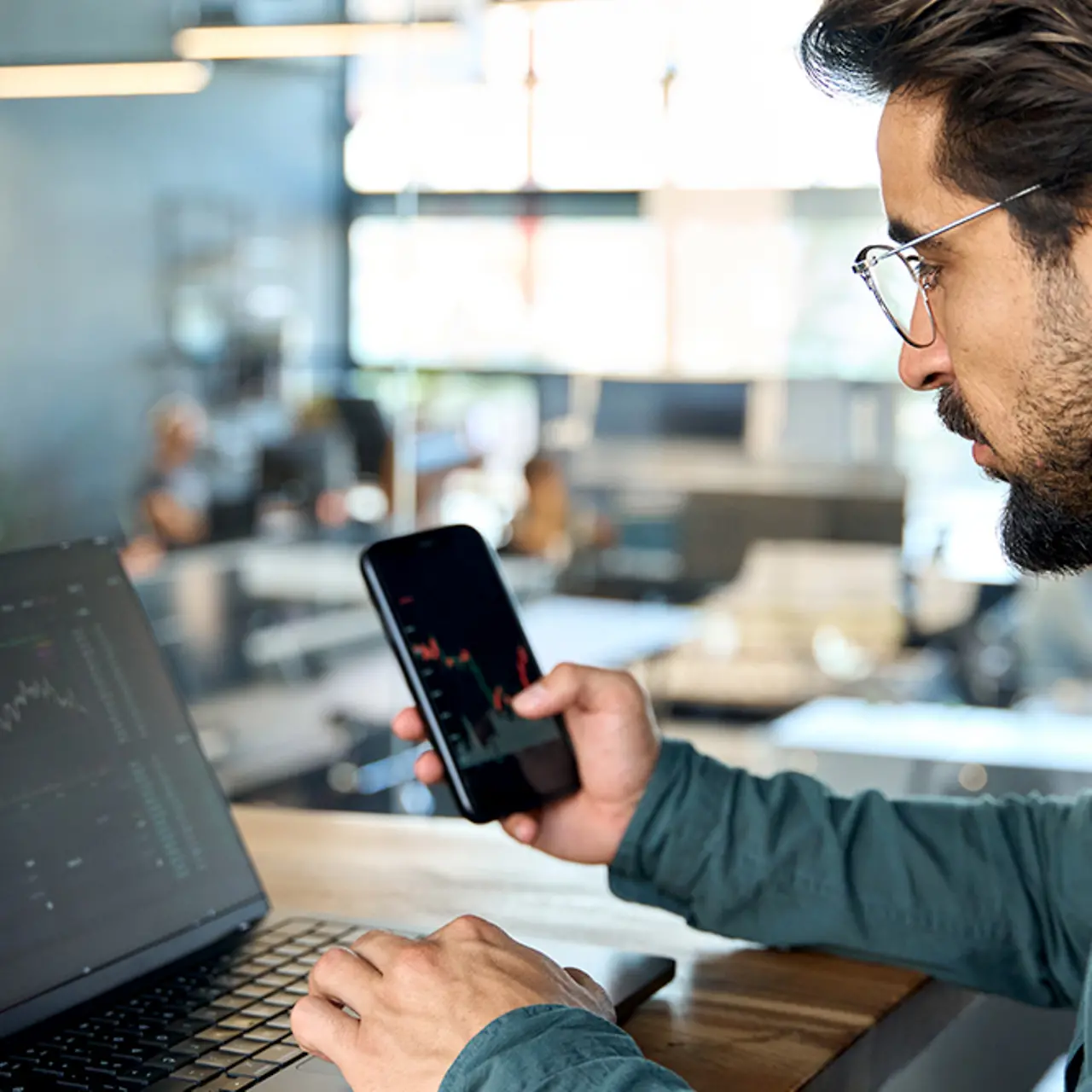 Investeringsmakelaar voor de laptop op kantoor met mobiele telefoon analyseert financiële cijfers