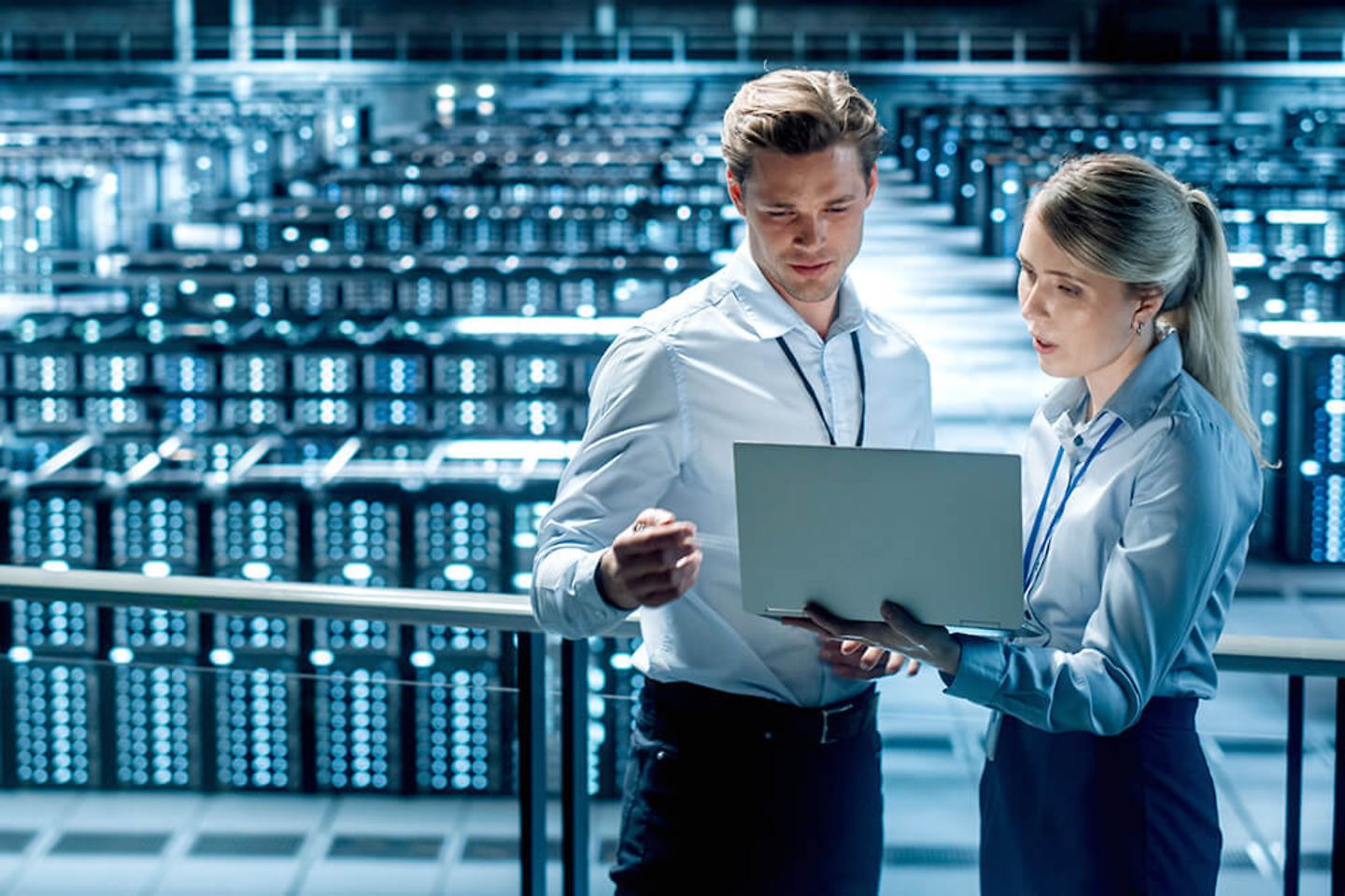 Retail IT specialists with laptop hold discussions in a computer server room.