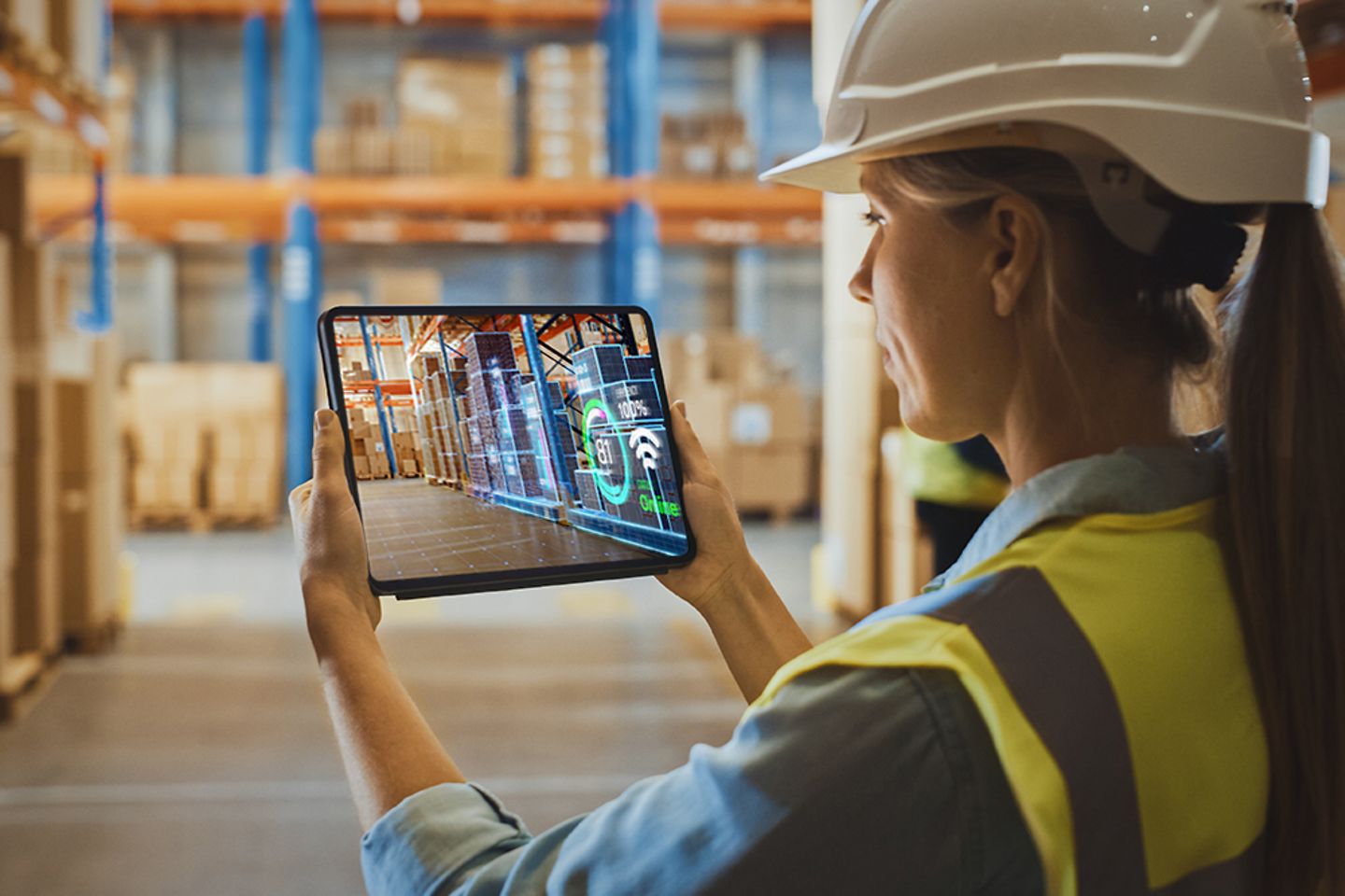 Female worker making an inventory of stock, using an augmented reality application on a tablet in a technology warehouse