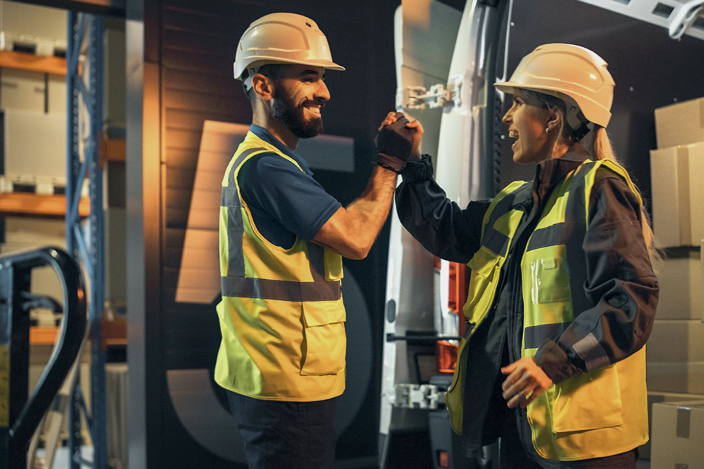 Delivery workers high-five next to delivery truck and parcels, packets