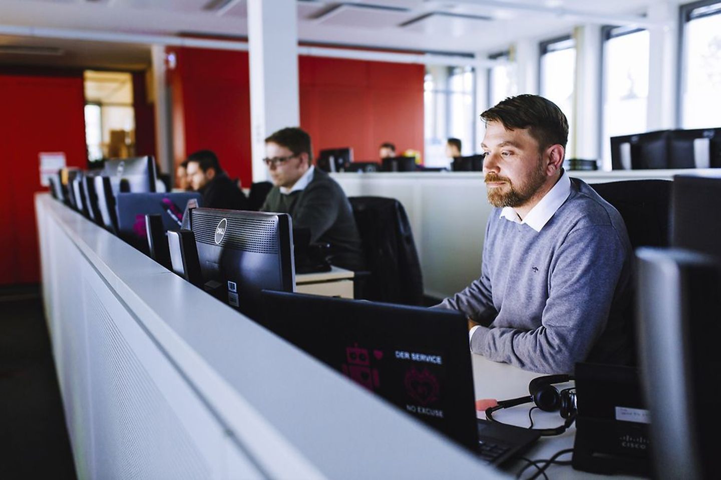 Businessmen, analysts sitting in office in front of computers