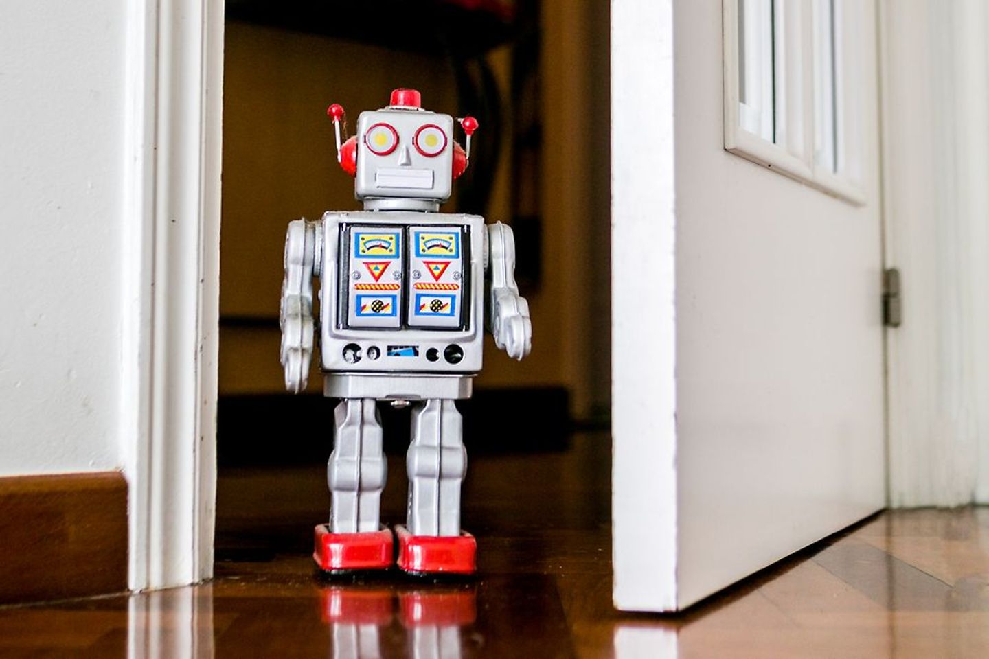 A friendly robot enters through an open office door