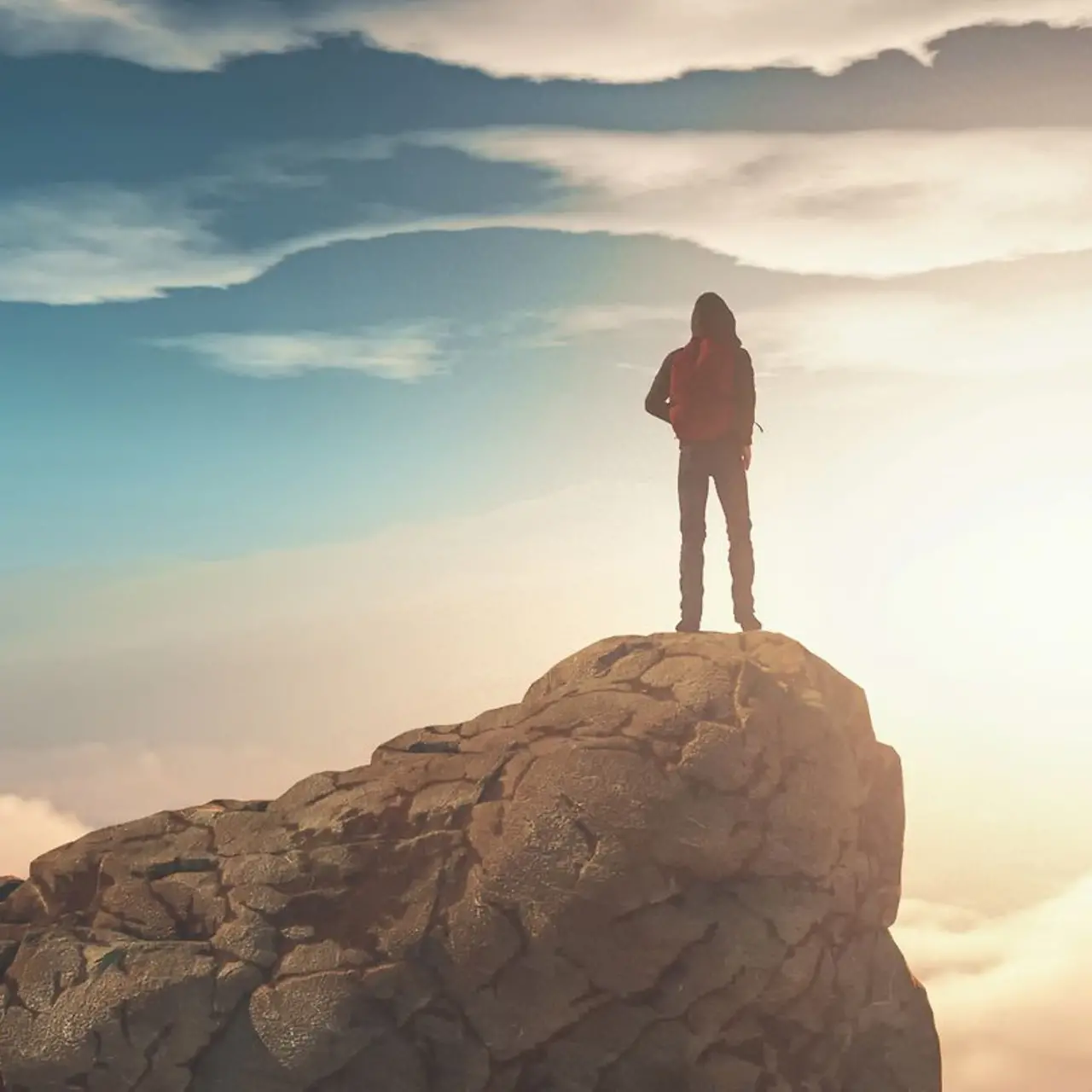 Un homme se tient au sommet d’une montagne entourée de nuages