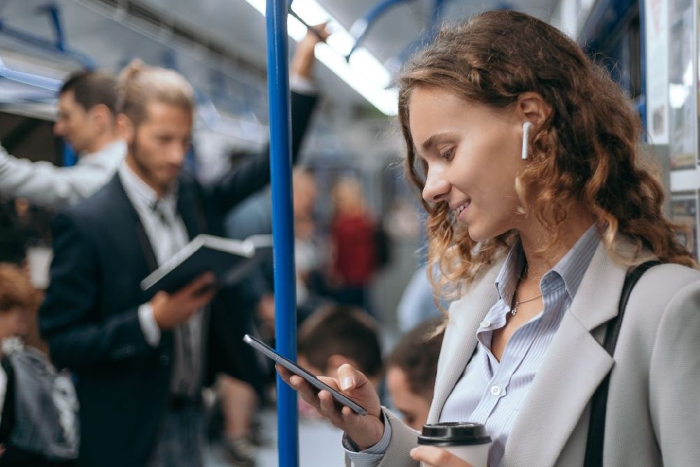 Businesswoman taking the subway to her office reads smartphone