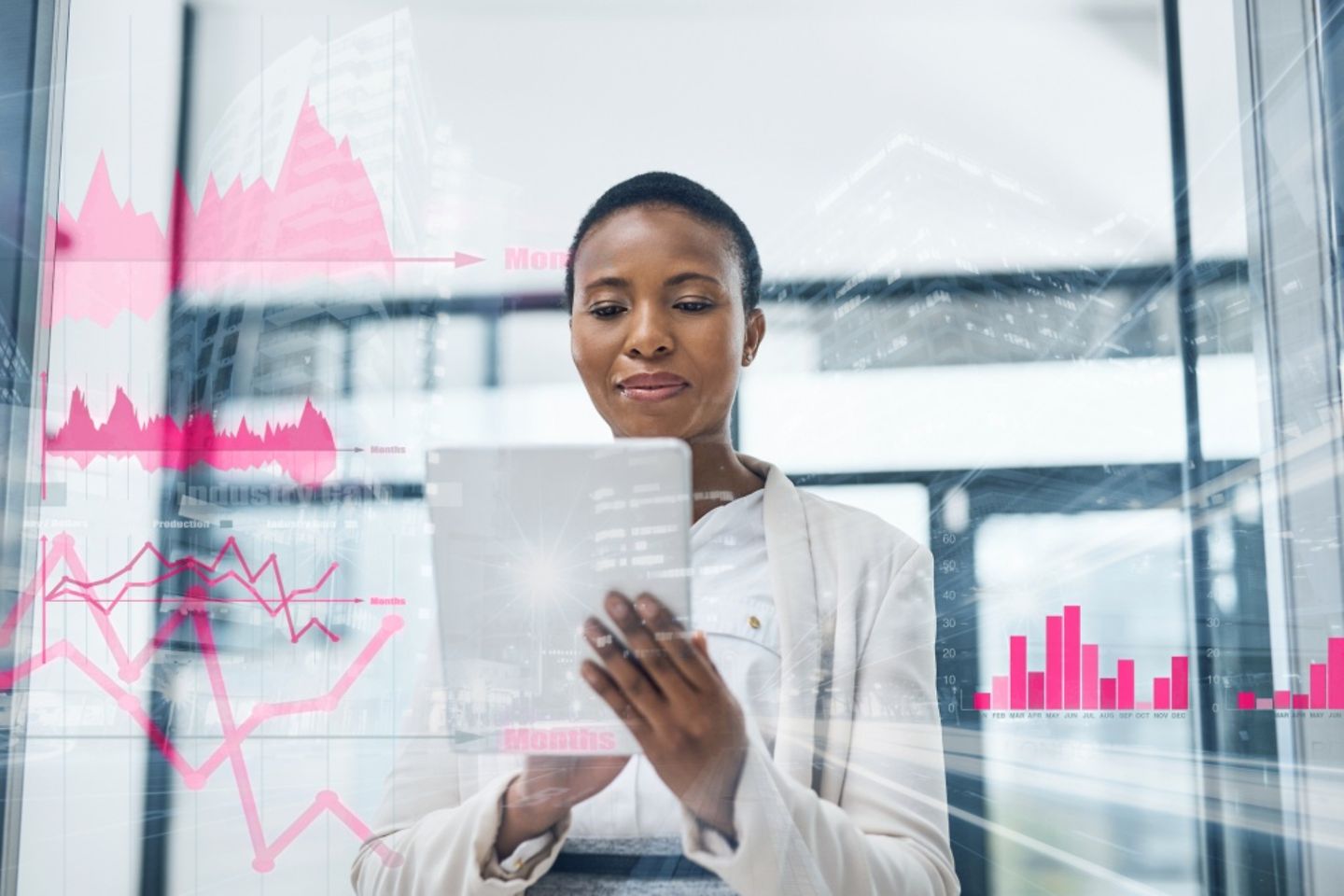 Femme avec un tablette devant une baie vitrée avec des graphiques et des diagrammes en magenta.