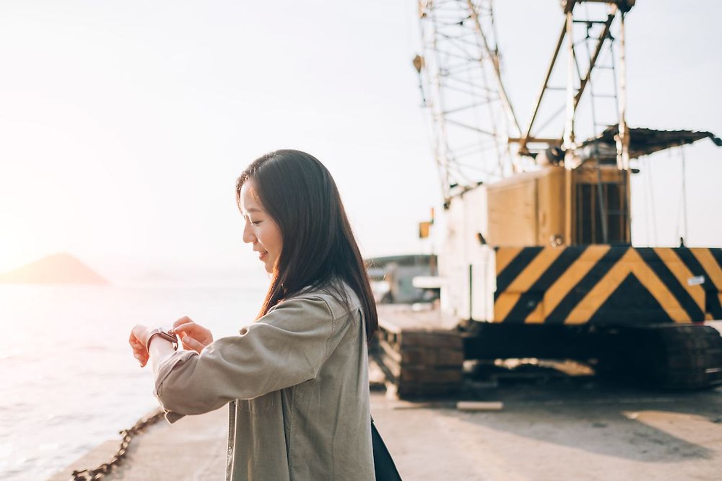 Frau schaut auf ihre Smart Watch in einem Industriehafen