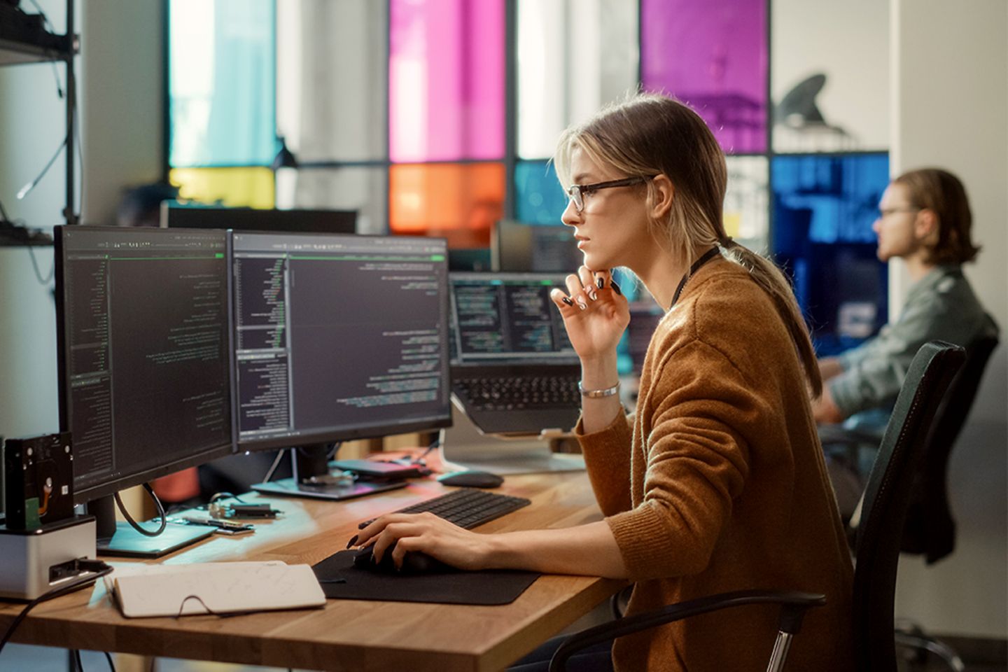 Female software developer uses multiple screens on computer