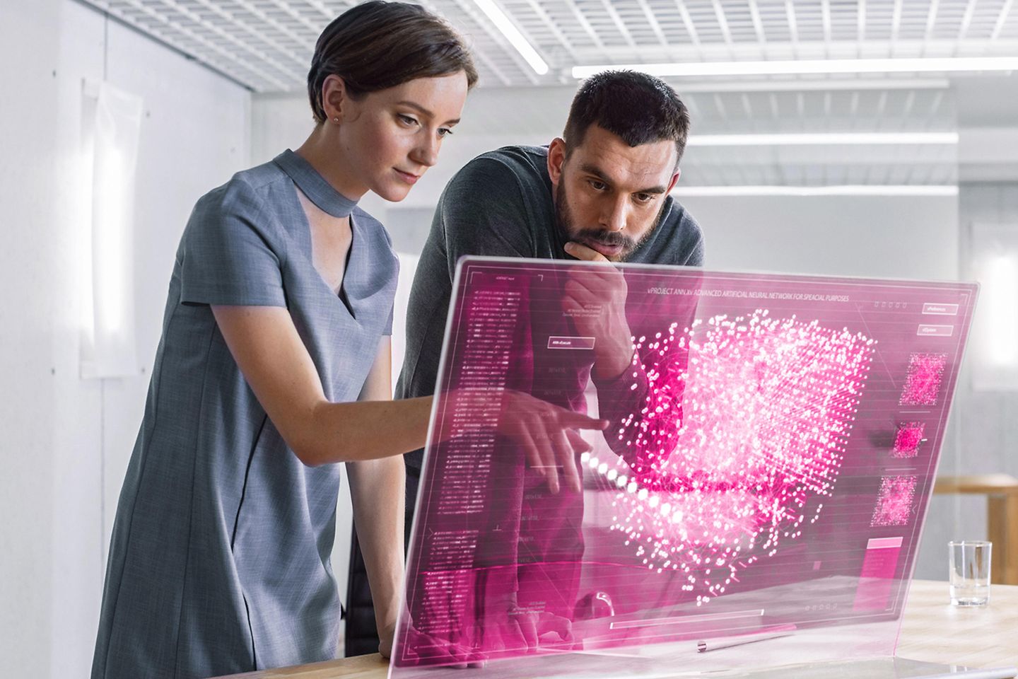 En un futuro próximo, dos ingenieros informáticos hablan mientras trabajan en un ordenador de pantalla transparente. 