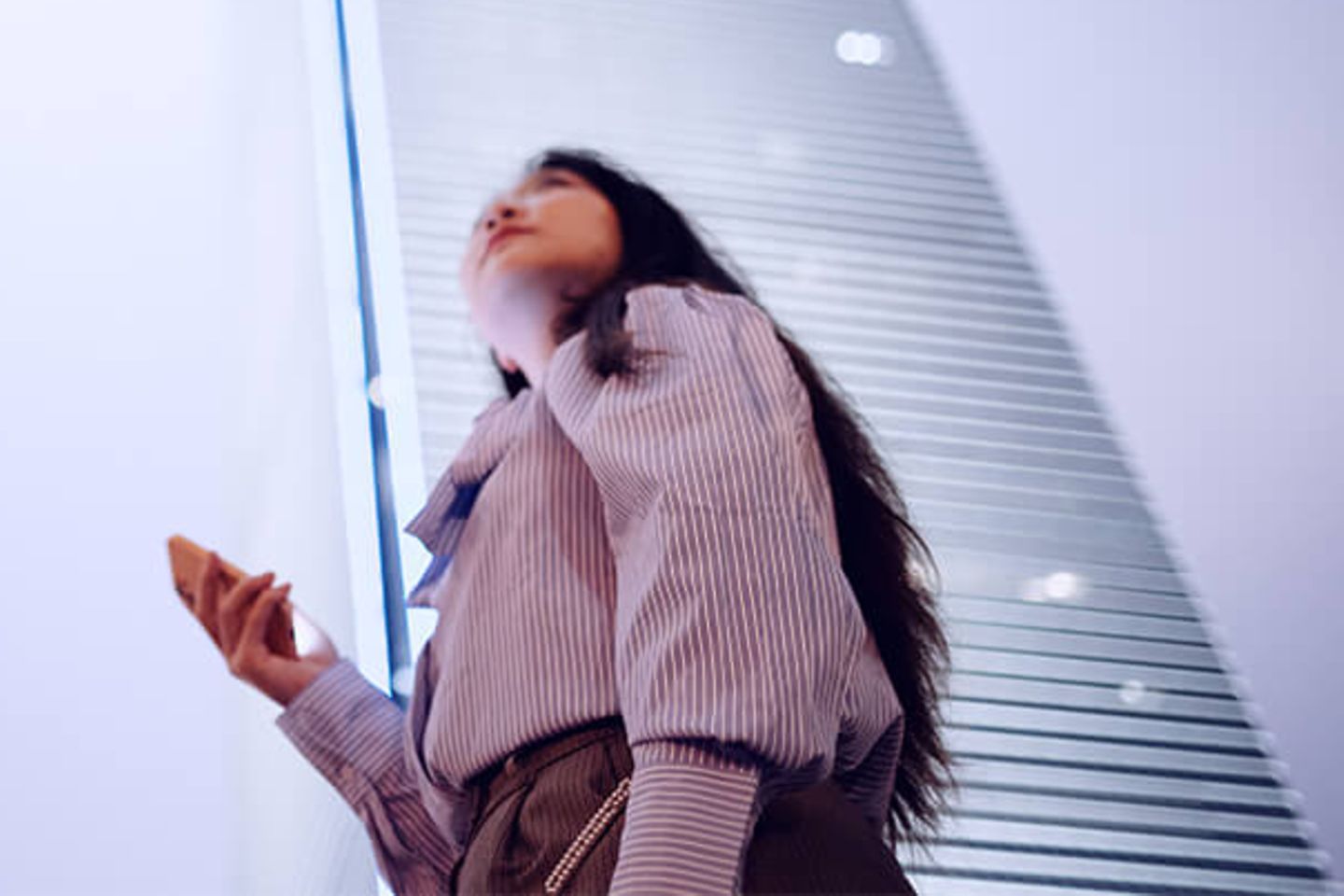 Woman with smartphone looking up to office skyscrapers