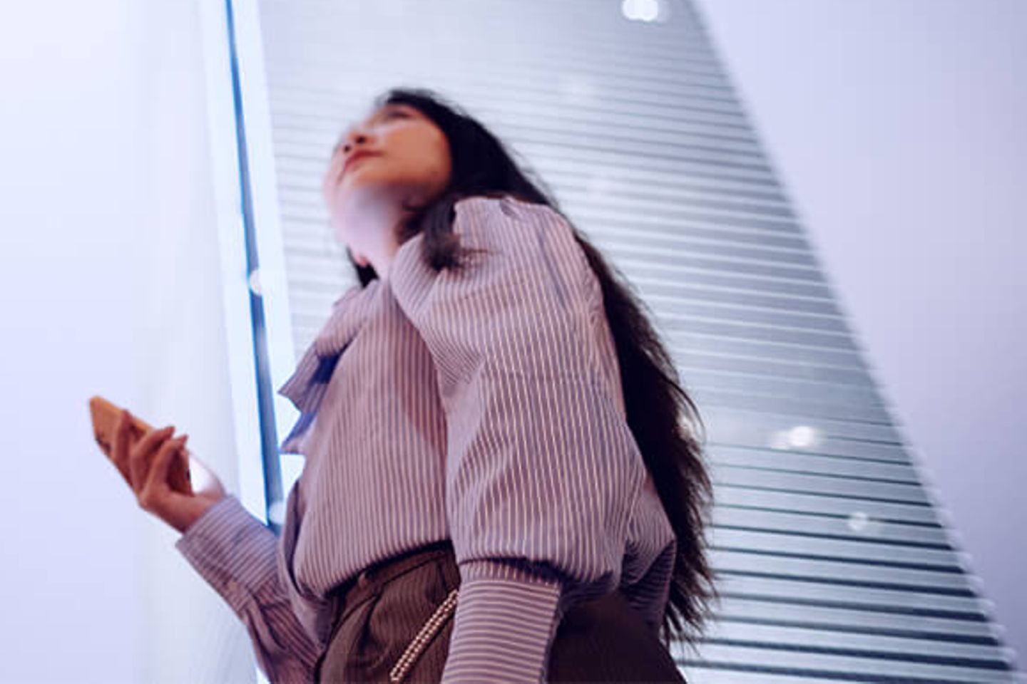 Woman with smartphone looking up to office skyscrapers