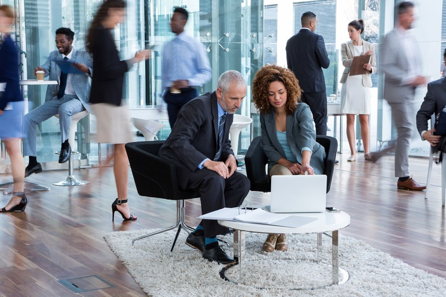 Businesspeople discussing data transformation at a table with a laptop on it