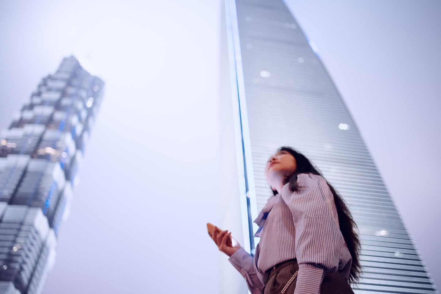 Female customer using cloud on mobile phone in front of building